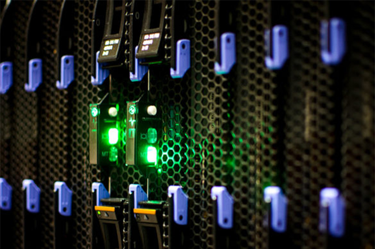 Image of racked server components with green lights.