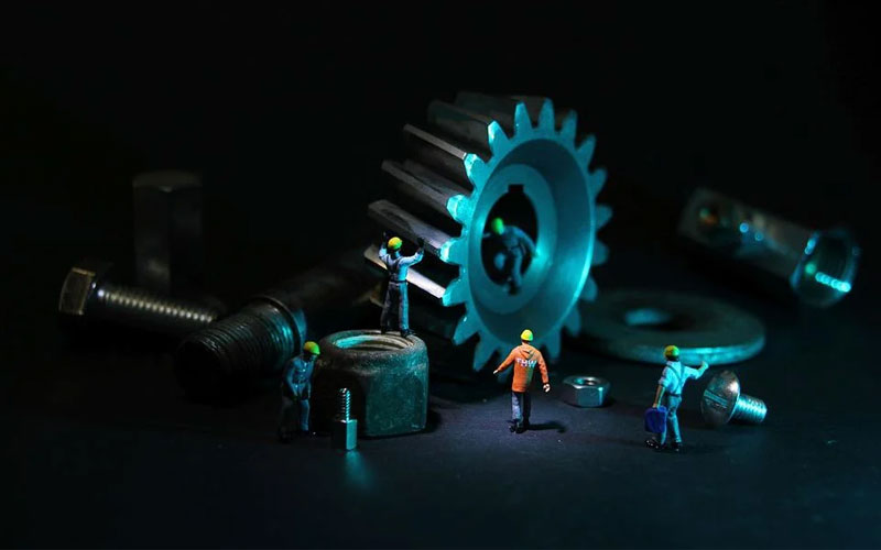 Image of a group of miniature workers assembling large mechanical parts.