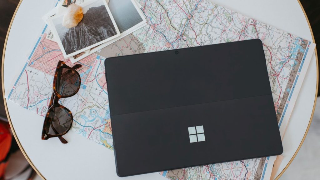 A graphic image of Microsoft surface over a map with sunglasses and polaroids aside.