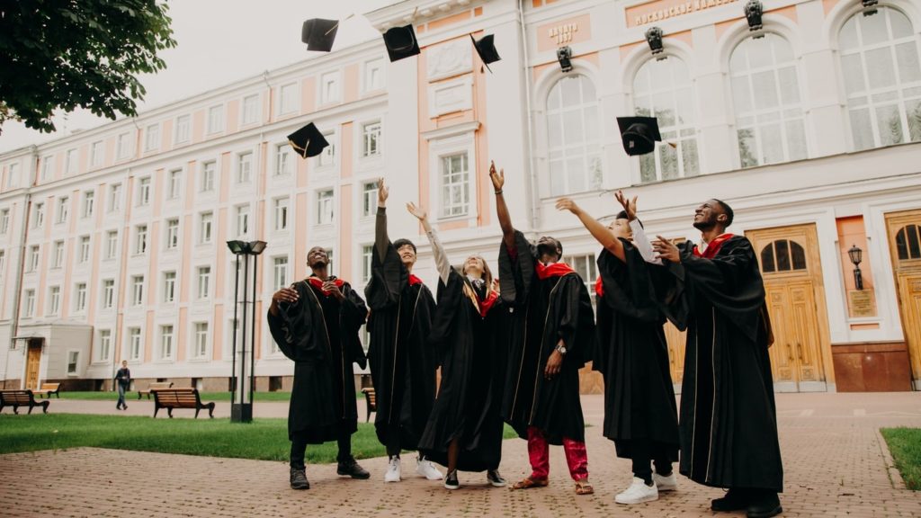 Image of student graduates celebrating in a university courtyard