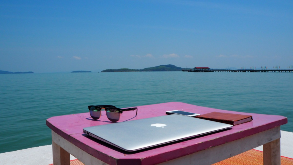 photograph of a closed laptop on a desk overlooking a tropical bay.