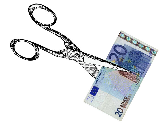 Image of a pair of scissors cutting a 20 euro bill.