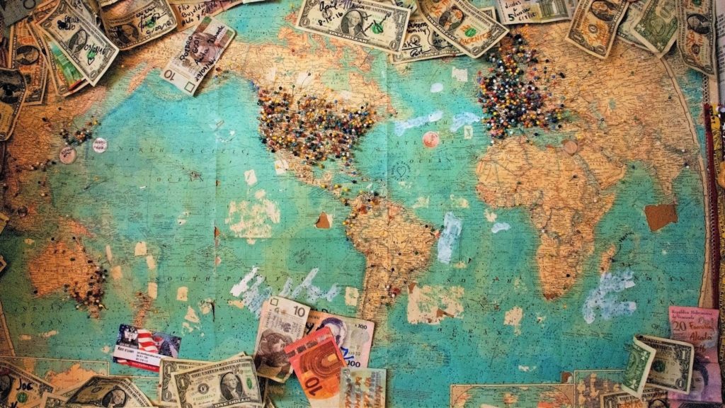 Image of a Mercator projection map with pins and money sitting on top of it.