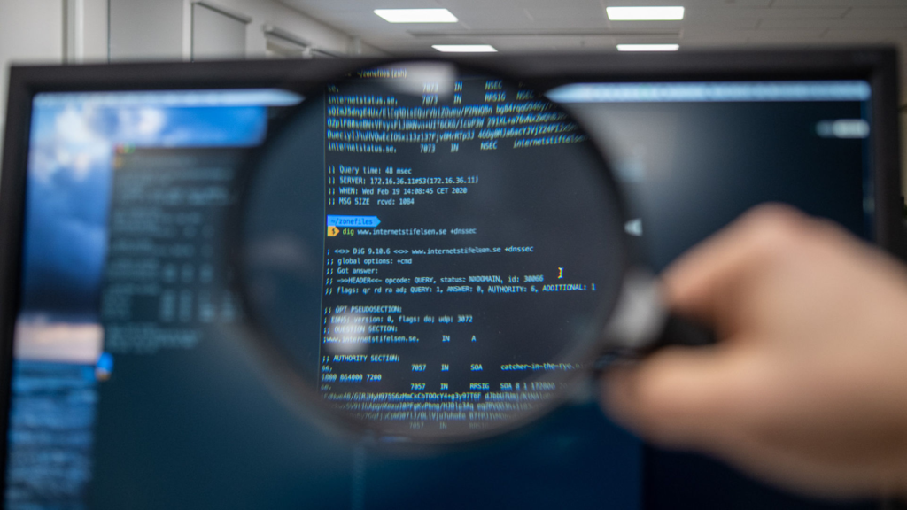Photograph of a magnifying glass in front of a monitor with a command window open.