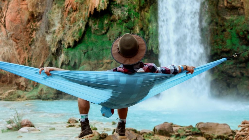 Image of a person laying in a hammock in front of a waterfall relaxing.
