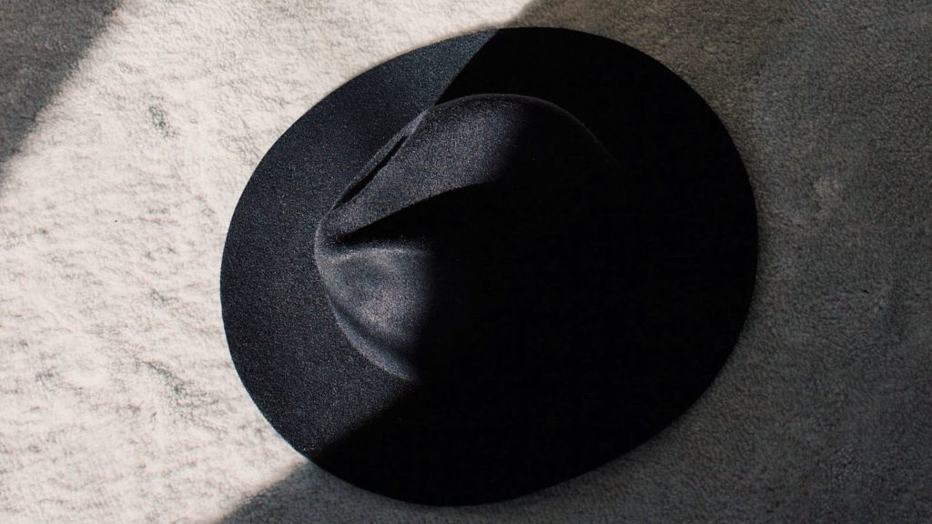 Image of a black Hat dropped on a shaggy gray flor.