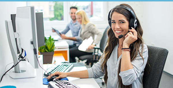 Image of a woman smiling while helping customers over a call.
