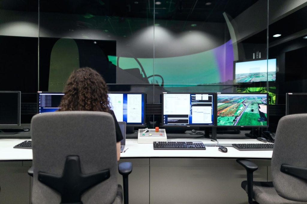 A woman sits at a computer in a command center, watching out for security threats.
