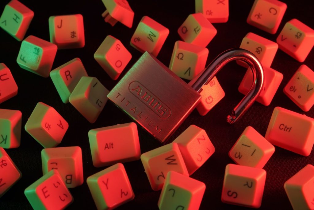 Image of an open padlock with computer keys floating in the background.