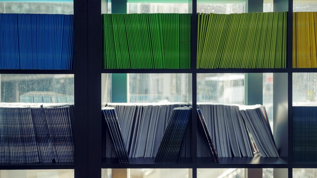 Image of rows of color-coded folders with office windows in the background.