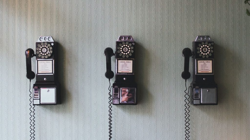 An image of three vintage phones on a wall.