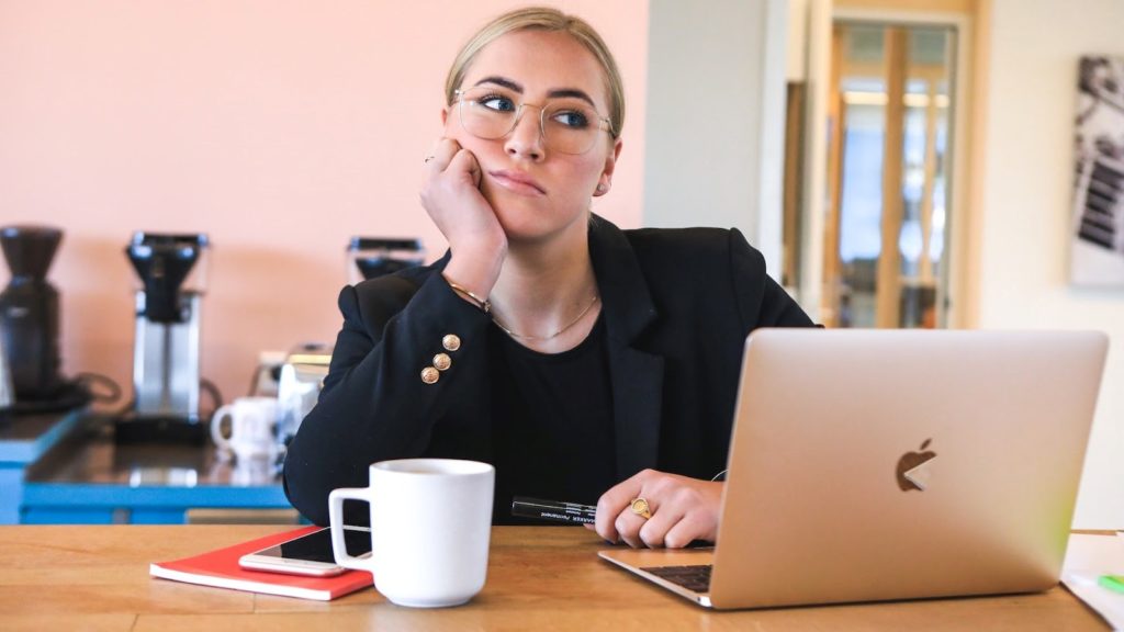 Image of woman looking annoyed behind a laptop.