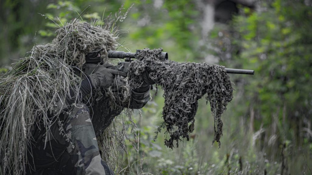 A graphic image of an airsoft sniper, waiting and aiming, player in camouflage.