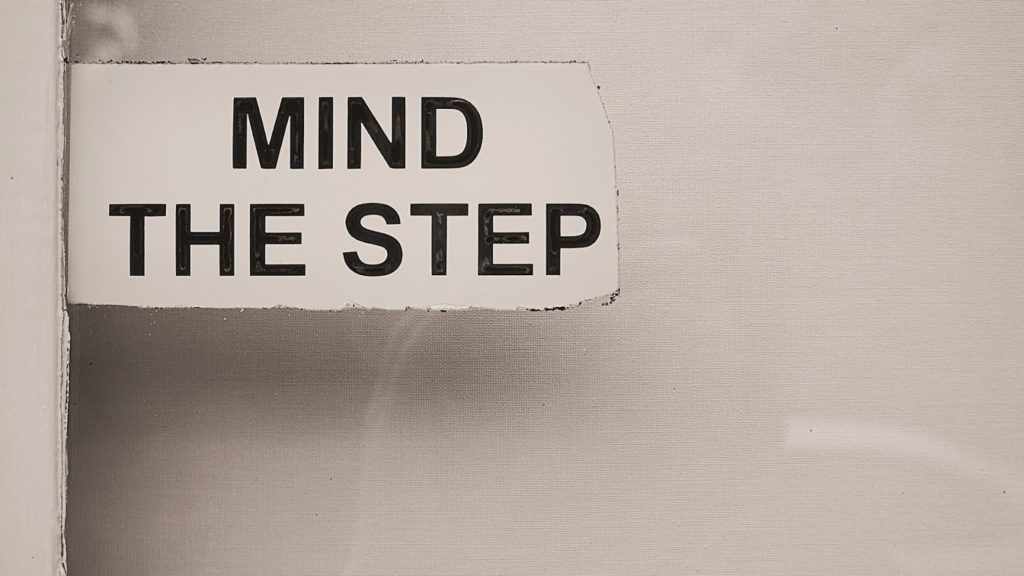 Image of a sign with the words "MIND THE STEP" on it.