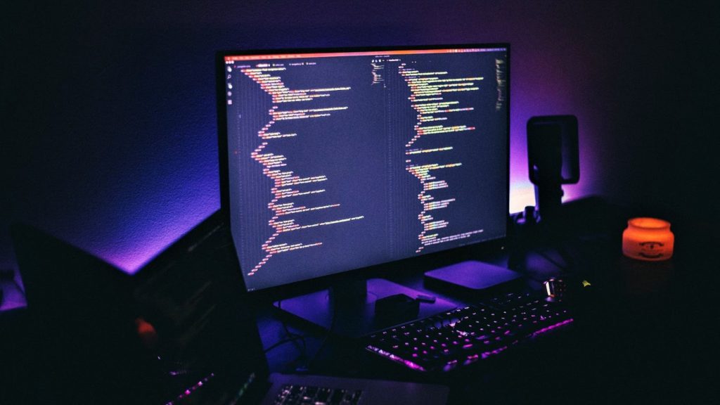 Image of a PC showing lines of code against a purple backlit background.