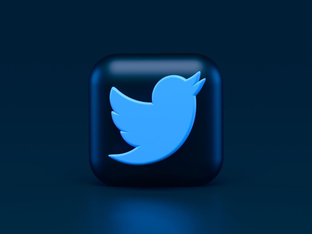 The image shows a bright blue Twitter logo against a dark blue background.