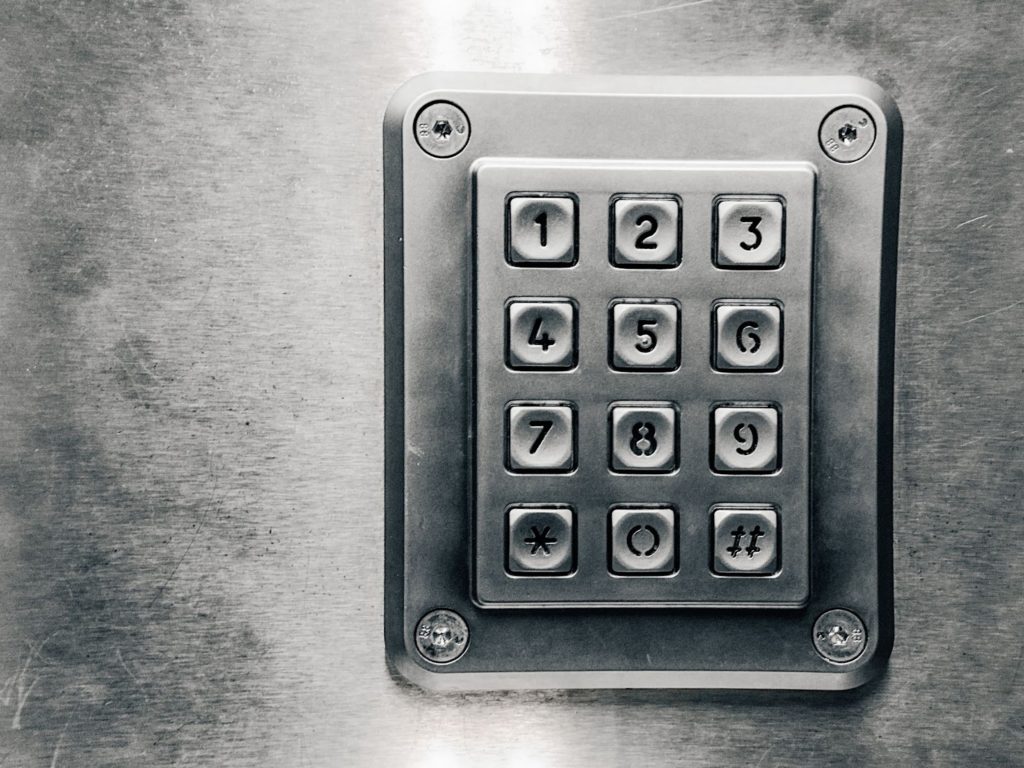A metallic silver security keypad bolted against a metallic silver background. 
