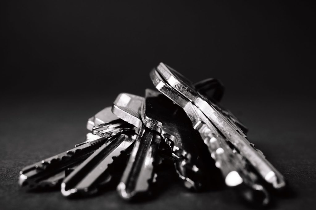 The image shows a bunch of silver keys on a black surface.