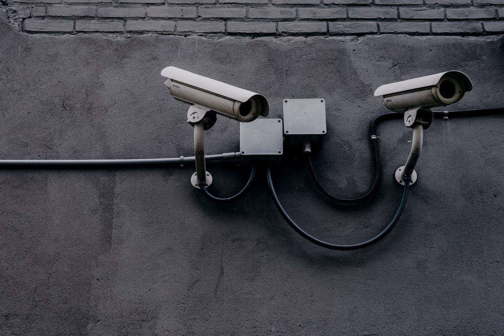 Image of two security cameras on a concrete wall.