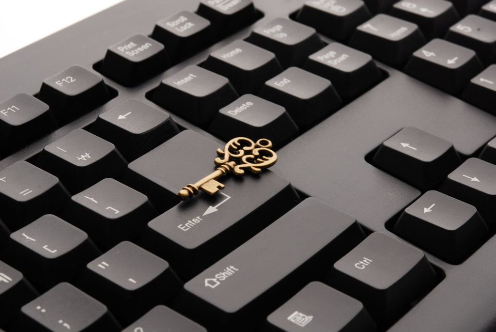 The image shows a small golden key on top of a black keyboard.