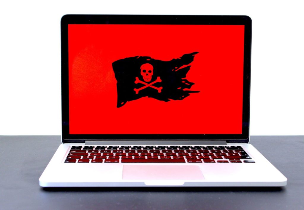 The image shows a computer with a red screen and a black pirate skull-and-bones flag.