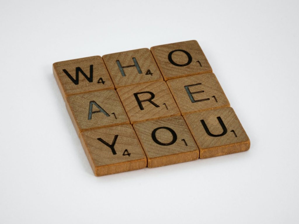 The image shows nine brown wooden blocks spelling out the words "Who Are You."